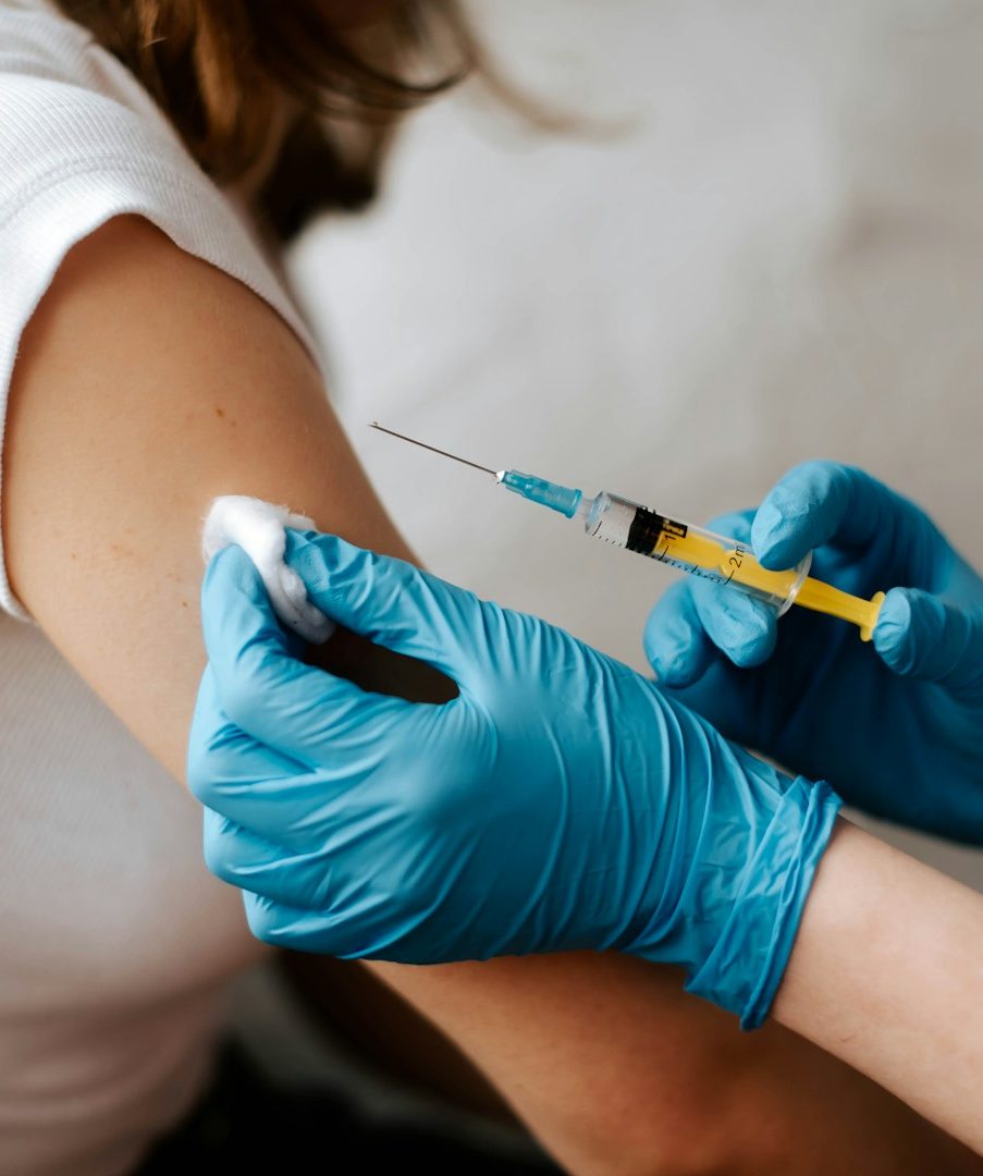 Hand mit Spritze injiziert einen Impfstoff in den Oberarm.