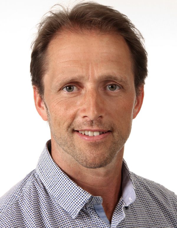 Porträt eines Mannes mit kurzen, braunen Haaren und einem freundlichen Lächeln.