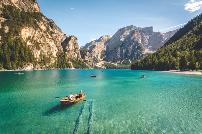 Boote auf türkisblauem Wasser vor beeindruckenden Bergen und einem klaren Himmel.